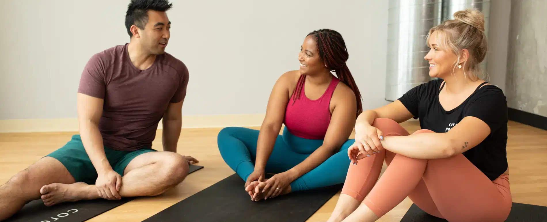 Group of friends in a yoga studio huddling together on their CorePower mats